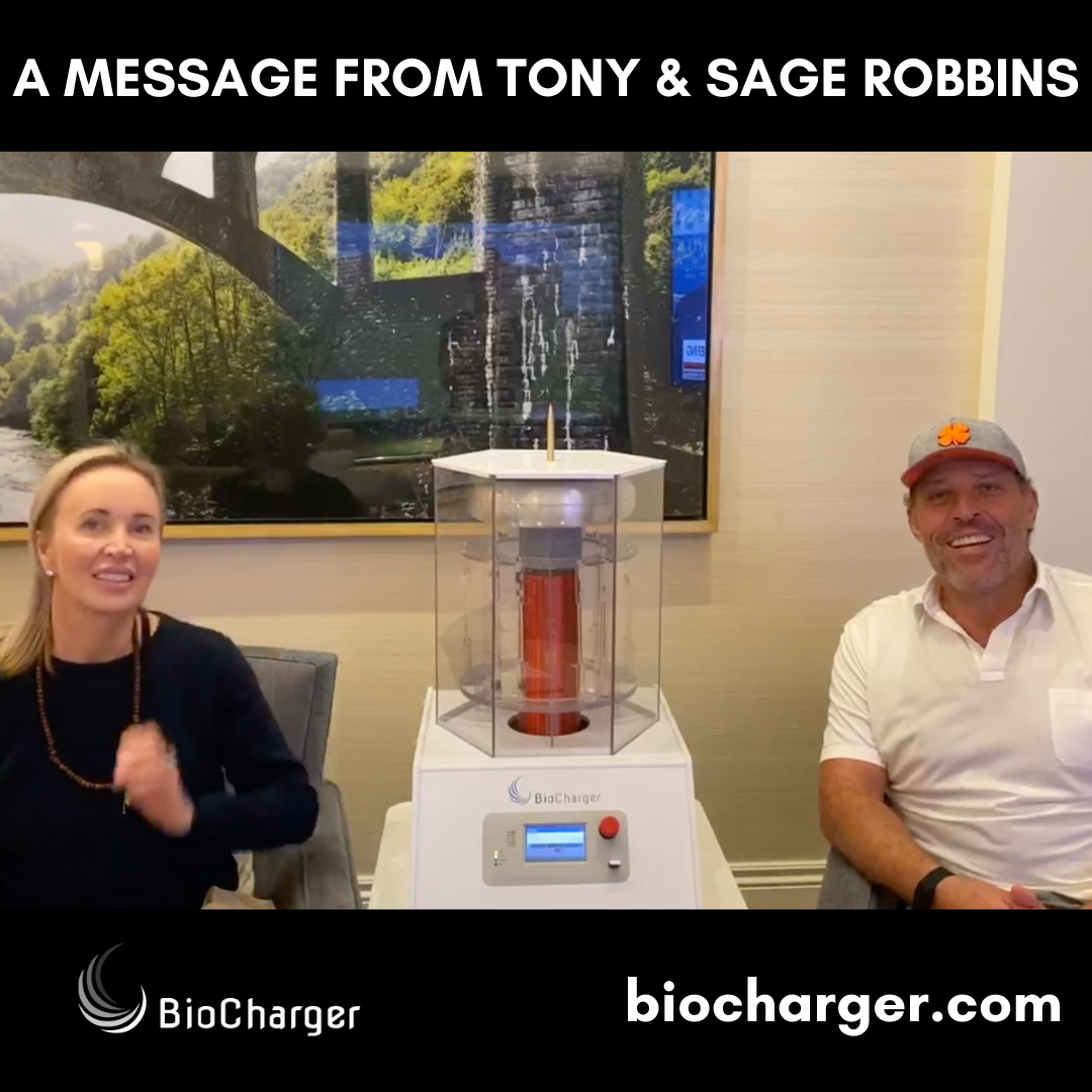 Sage and Tony Robbins Sitting and Smiling with BioCharger Device Between Them