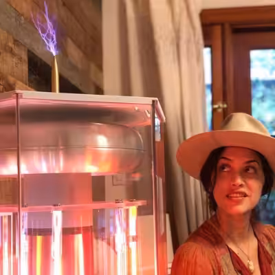Woman Sitting Next to the Working BioCharger Device and Looking at Arc Rode
