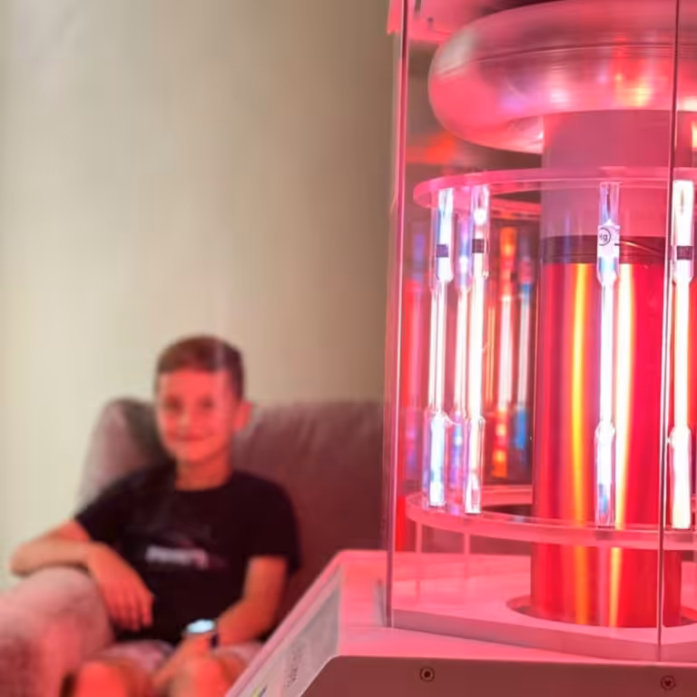 Young Boy in Black T-Shirt Smiling and Sitting Behind Working BioCharger Device
