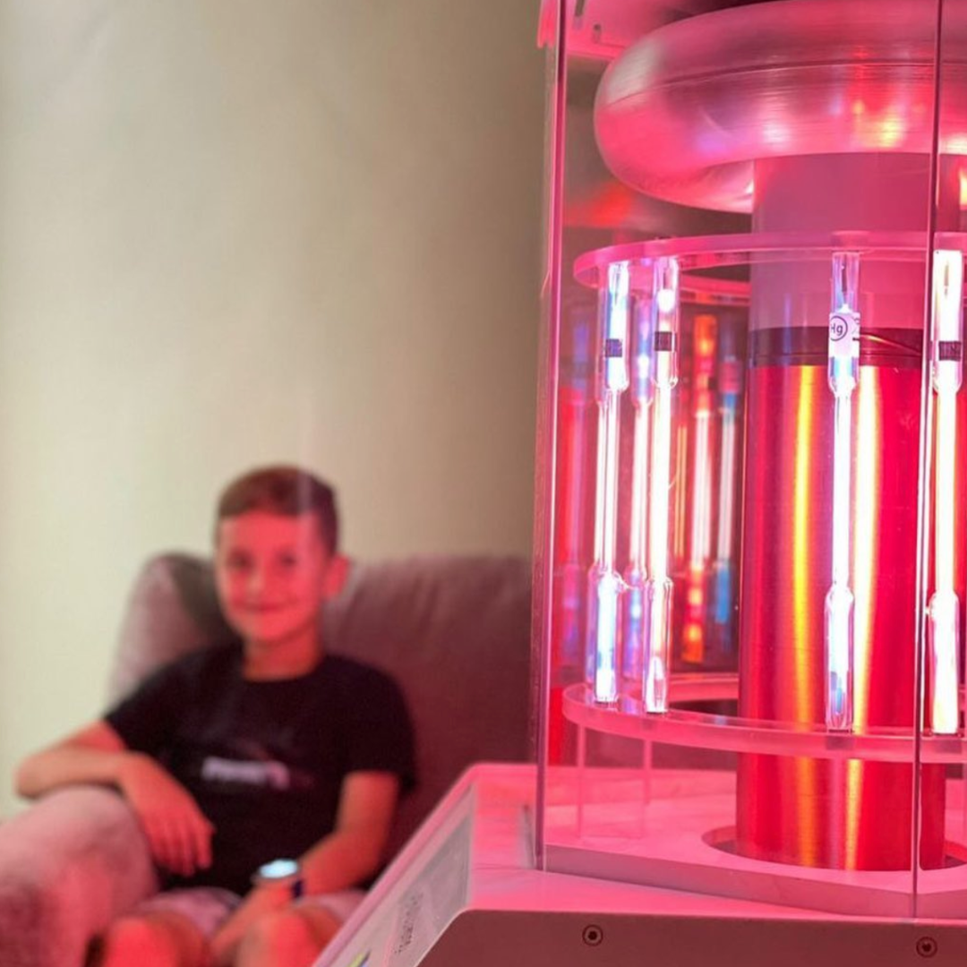 Young Boy in Black T-Shirt Smiling and Sitting Behind Working BioCharger Device