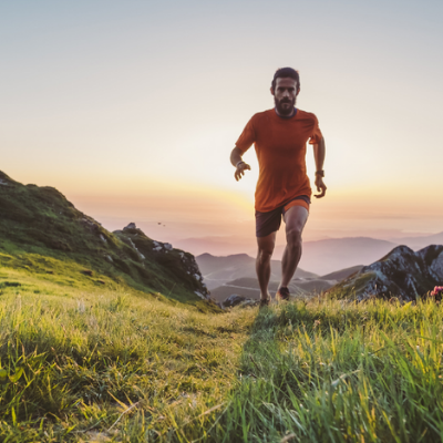 Man in Orange T-Shirt is Running on the Mountain with Beautiful Sunset in the Background