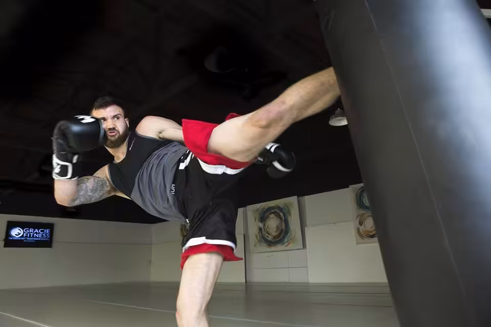 Sean Lally Performing Low Kick on a Boxing Bag