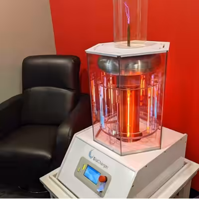A Working BioCharger Device Standing on a desk Next to the Black Chair in a Room with Red Wall