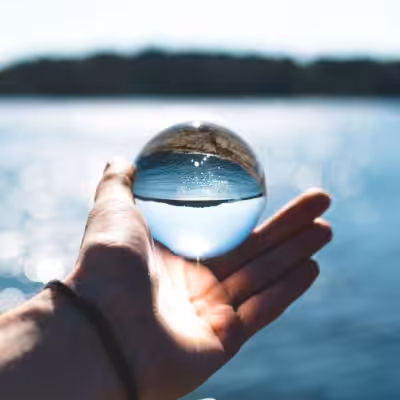 Hand Holding Crystal Ball and Showing the Beautiful Sea Through it