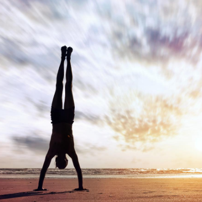 Woman Performing Handstand on a Beach Under Beautiful Sky