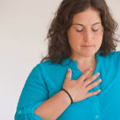 Cindy Huston Founder of Yoga Body Elements LLC with her Eyes Closed and Right Hand on Her Chest