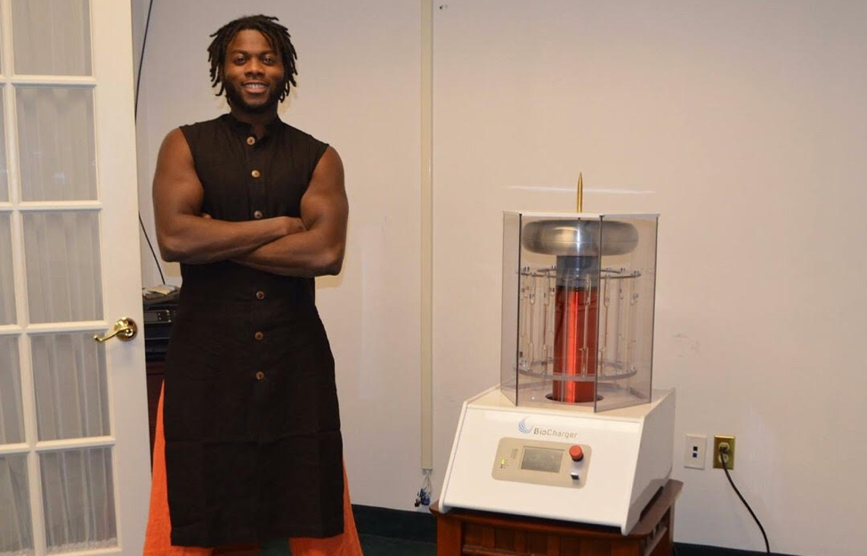Clayton Laguerre Standing Next to the BioCharger Device and Smiling