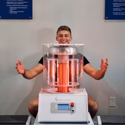 Young Man in Black T-Shirt Sitting Behind Working BioCharger Device With His Hands Raised
