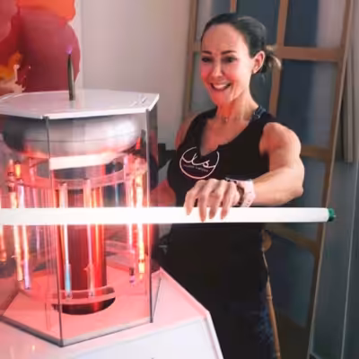 Woman in Black Shirt Standing Behind Activated BioCharger Device Holding Long Fluorescent Bulb In Front of It