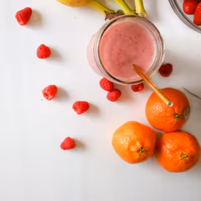 Raspberry Smoothie in the Glass Standing on the Table Surrounded by Fruits