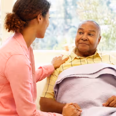 Young Woman Comforts Mature Man by Holding His Hand and Shoulder