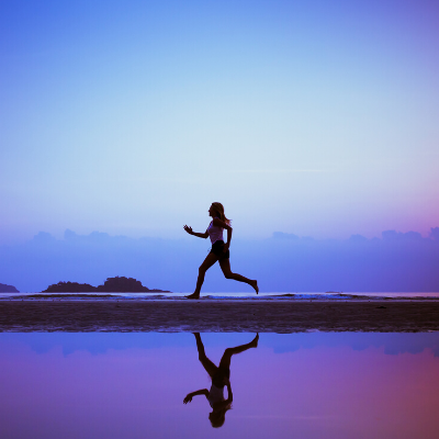 Female Running Next to the Water with Reflection and a Beautiful Purple Sky in the Background