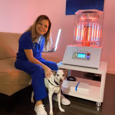 Woman Smiling and Sitting with a Dog and Holding Bulb Next to the Working BioCharger Device