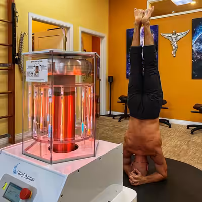 Man Standing on His Head Behind the Working BioCharger Device In The Life Center Chiropractic