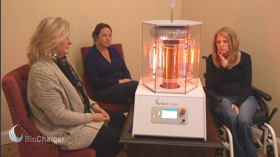Three Women Sitting around Activated BioCharger Device