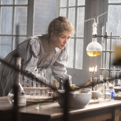 Rosamund Pike Portraying Marie Curie Experimenting in Her Lab