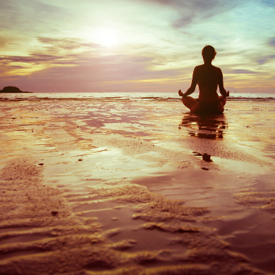 Female Sitting in a Lotus Position on the Beach and Watching at the Beautiful Sky