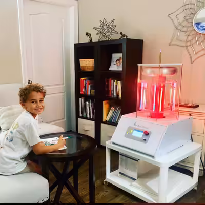 Smiling Child Sitting and Drawing Next to the Working BioCharger Device
