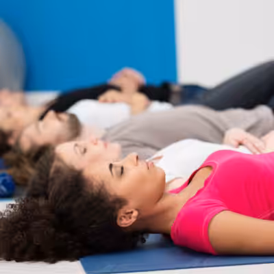 Relaxed Group of People Laying on Yoga Mats in Yoga Class