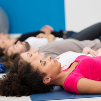 Relaxed Group of People Laying on Yoga Mats in Yoga Class
