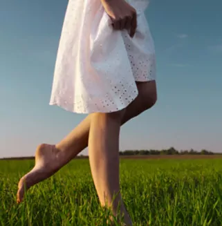 Barefooted Women in a White Dress walking on Grass