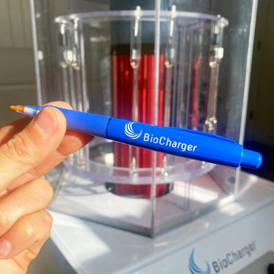 Hand Holding BioCharger Pen In Front of the BioCharger Device