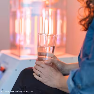 Woman Sitting Next to a Working BioCharger Device and Holding Her Glass of Water in Her Hands