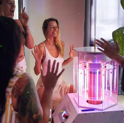 Group of People With Their Hands in the Air Standing Around the Working BioCharger Device