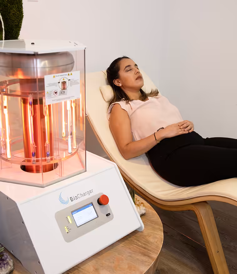 Woman in a Baby Pink Shirt with Closed Eyes Lying Next to the Working BioCharger Device