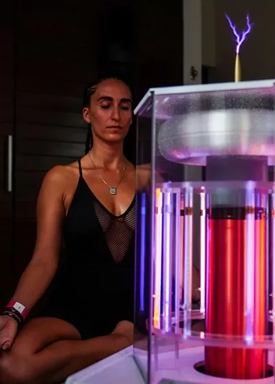 Woman Meditating Behind the Working BioCharger Device
