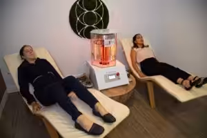 Two Women Lying With their Eyes Closed and Working BioCharger Device Between Them