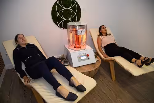 Two Women Lying With their Eyes Closed and Working BioCharger Device Between Them