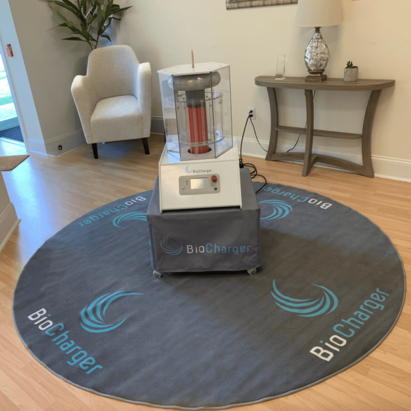 round grey rug with a blue and white BioCharger logo on it and a BioCharger sitting on top of a grey table