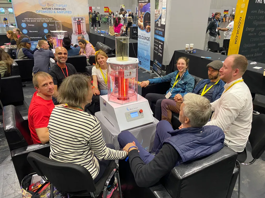 Eight People Holding Hands Sitting in Front Of The BioCharger Device