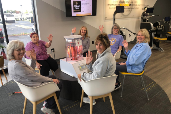 6 women surrounded a BioCharger in a circle waving to the camera to say hi