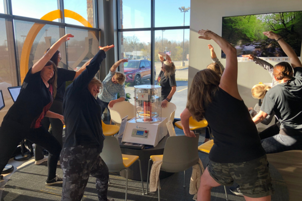 A group of women in athletic clothing participating in gentle stretching around the BioCharger